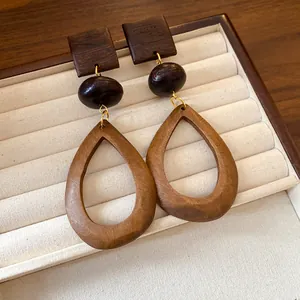 Close-up view of New Chinese style wooden teardrop earrings with retro ethnic texture.