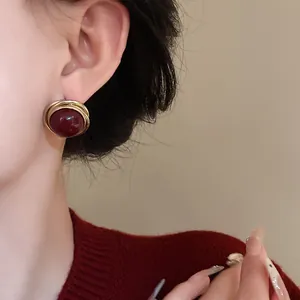 Primer plano de pendientes vintage con perlas rojo oscuro y envoltura de alambre dorado