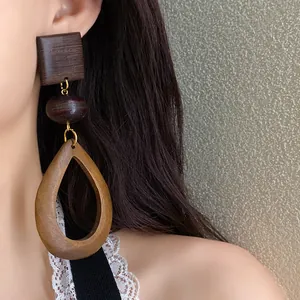 Close-up of ethnic style wooden teardrop earrings on model's ear