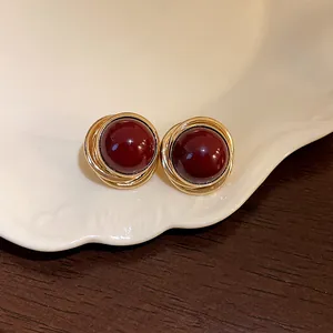 Detalle de pendientes vintage de perlas rojas con un diseño envolvente dorado.