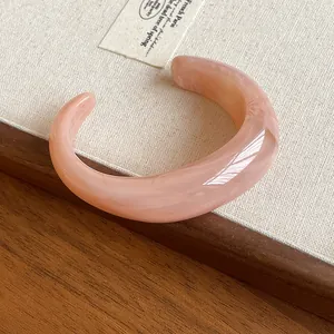 Close-up of a marbled pink acrylic open cuff bracelet with a smooth glossy finish