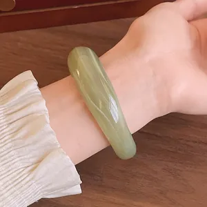 Close-up of an elegant light green marbled acrylic bangle bracelet on a woman's wrist