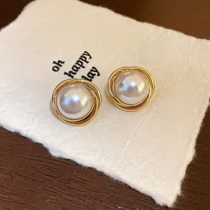 Primer plano de pendientes de perlas retro con diseño de alambre de oro envuelto.