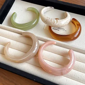 Detailed view of colorful marbled acrylic open bangles in a jewelry display tray.