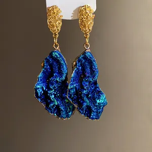 Close-up of vintage irregular drop earrings with deep blue geode pendants and gold studs.