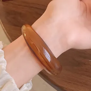 Close-up of a translucent amber acrylic bangle with elegant marbled swirl patterns