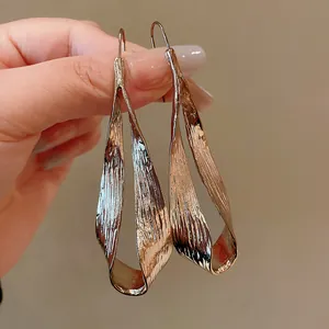 Detailed macro view of long irregular twisted metal statement earrings in a gold finish