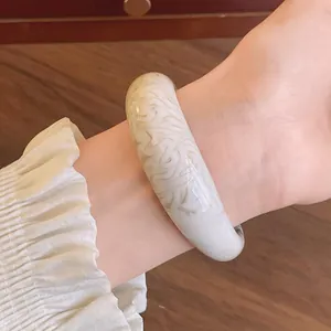 Detail showing the marbled texture of a white acrylic bangle on a woman's wrist.