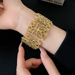 Primer plano de un brazalete ancho dorado con intrincados diseños de filigrana fina