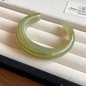 Close-up of a light green marbled acrylic cuff bracelet on a velvet display tray