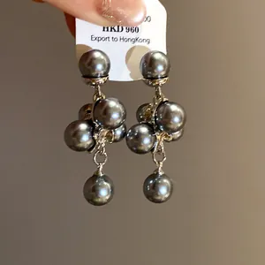 Detailed macro view of dark grey pearl grape cluster earrings with silver needle