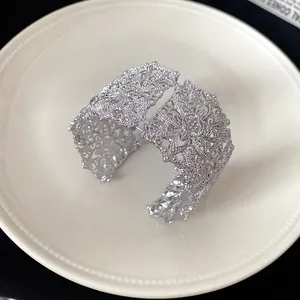 Primer plano del intrincado diseño floral calado en este brazalete ancho plateado