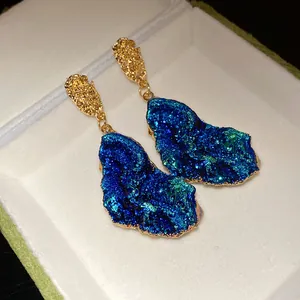 Close-up of irregular blue crystal-like drop earrings with gold finish