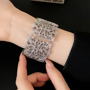 Primer plano de un brazalete ancho de filigrana plateada con intrincados calados.