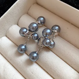 Elegant grey faux pearl grape cluster earrings displayed in a beige jewelry box tray