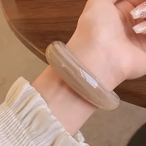 Detailed close-up of an elegant acrylic marbled bangle worn on a woman's wrist for a chic look