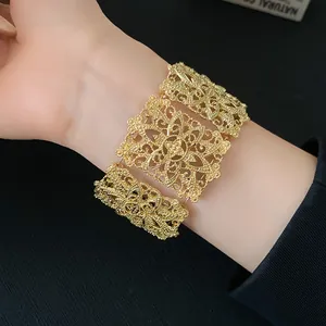 Primer plano de un brazalete ancho dorado con intrincados patrones florales calados vintage