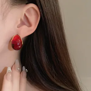Detailed macro close-up of vintage red water drop geometric earrings worn on the ear