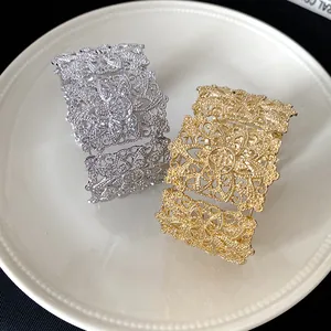 Vista detallada de brazaletes anchos con diseño floral calado en acabados de oro y plata