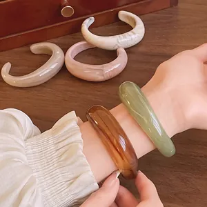 Close-up detail showing the elegant marbled texture of acrylic open bangles on a wrist