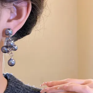 Detail view of French retro grape cluster earrings with black pearls and silver needles.