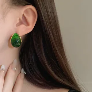 Vintage green resin teardrop stud earring with gold-tone setting shown on model ear