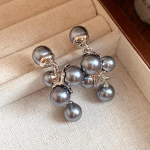 Close-up of elegant grey pearl grape cluster earrings presented in a beige jewelry box.