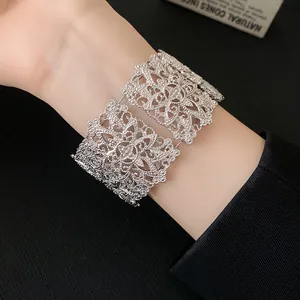 Vista detallada de un brazalete ancho plateado con intrincados patrones calados