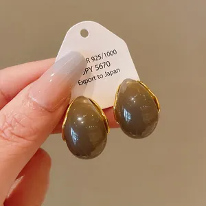 Close-up of vintage brown teardrop earrings with gold trim and silver needle