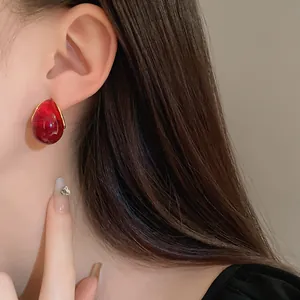 Macro detail shot of a vintage style red resin water-drop stud earring worn by a model