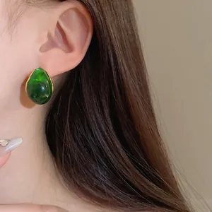 Close-up of vintage green waterdrop earrings worn on ear, showing retro geometric design.