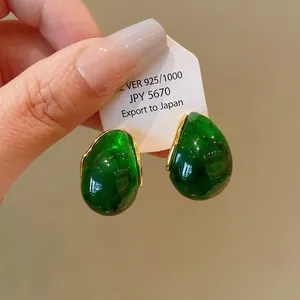 Detail view of translucent green water drop earrings with gold trim on a display card