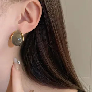 Macro view of vintage Maillard water drop earrings with grey stones on a female ear