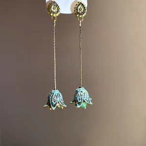 Dettaglio di orecchini a nappa a campana in smalto blu chiaro in stile boho con aghi d'argento.