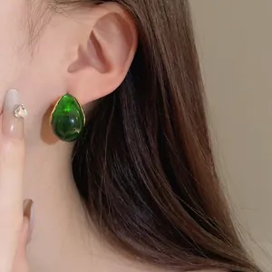 Elegant detail showing a vintage emerald green teardrop earring worn on a model's ear