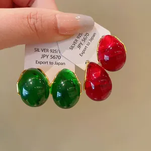 Close-up detail of retro water drop earrings featuring glossy green and red resin finish