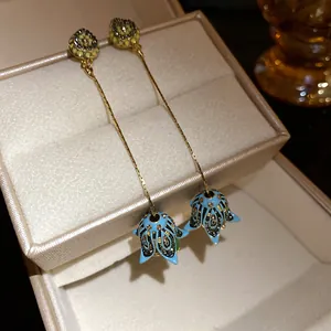 Dettaglio degli orecchini bohémien con nappe a fiori in smalto blu e strass brillanti
