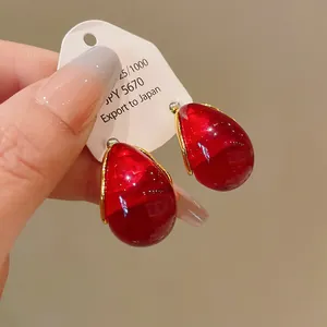 Close-up detail of vintage red water-drop geometric earrings with silver pins on card