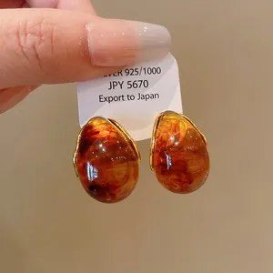 Macro view of vintage amber teardrop earrings with S925 silver needle on a white export tag