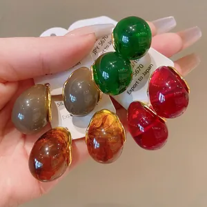 Close-up of retro colorful teardrop geometric resin earrings in amber and red colors