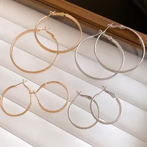 Detail view of round pleated textured gold and silver hoop earrings in multiple sizes