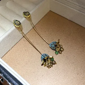 Dettaglio di orecchini boho con nappine a fiore in smalto blu in scatola portagioie