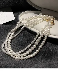 Vue détaillée d'un collier de perles vintage français à trois rangs avec fermoir doré.