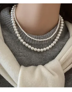 Gros plan d'un élégant collier de perles blanches à double rang sur un mannequin en tricot