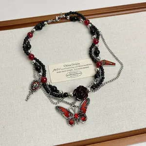 Vista detallada de un collar de cuentas de estilo gótico con colgantes de mariposa y rosa.