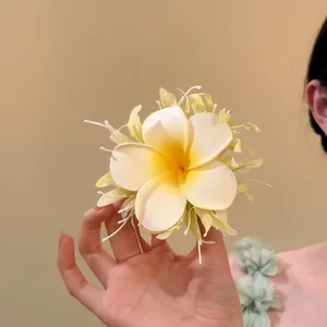 Detailaufnahme einer weiß-gelben Frangipani Stoffblumen-Haarklammer in der Hand