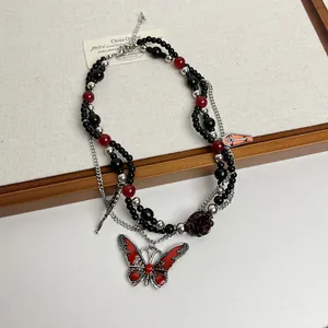 Vista detallada del colgante de mariposa gótica en un collar de cuentas negras y rojas