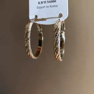 Close-up view of elegant textured round hoop earrings with a pleated twill pattern
