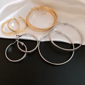 Detailed view of textured gold and silver hoop earrings on satin fabric background