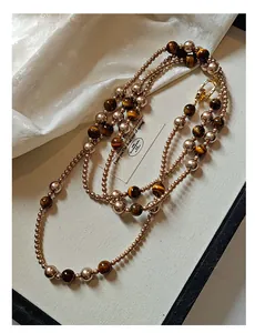 Detailansicht einer vintage Pulloverkette mit Tigerauge-Steinen und Kunstperlen.